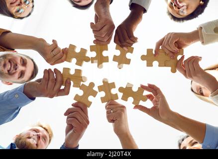 Happy successful business team putting together puzzle pieces during coaching training. Stock Photo