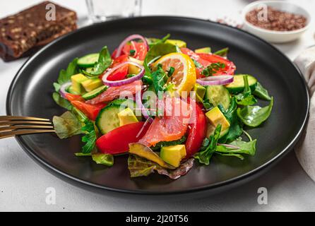 Salad with salmon, avocado and vegetables on a gray background. Side view, close-up.Side view, close-up. Stock Photo