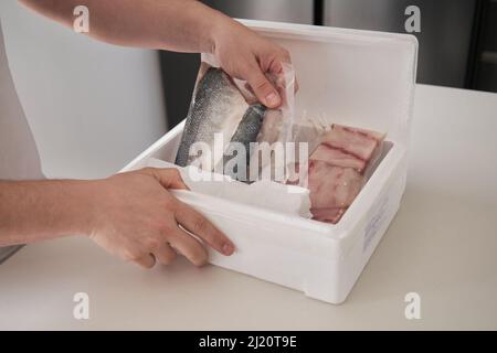 Unrecognizable person opening his weekly delivery of fish in an isothermal box. Stock Photo