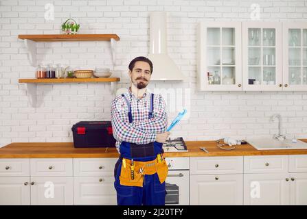 Portrait of professional male plumber in overalls posing in kitchen of apartment. Stock Photo