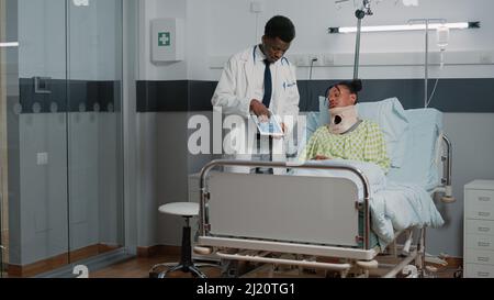 Specialist explaining radiography to woman with neck collar in hospital ...