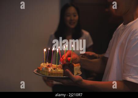 Man holding birthday cake with candles for birthday girl in the house. Stock Photo