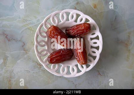 Date fruit in bowl on colorful marble background, top view Stock Photo