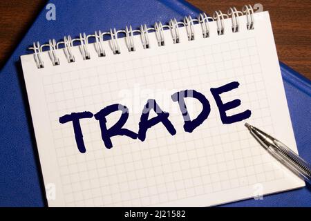 TRADE word on white table through craft torn paper. flat lay, top view. Stock Photo