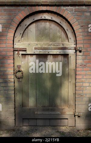 Old classic simple wooden door in a stone wall Stock Photo