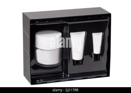 Closeup of a opened decorative black cosmetic box or gift box with label-free white tubes and containers isolated on a white background. Macro. Stock Photo