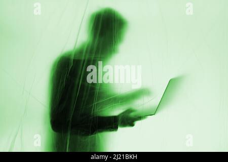 Anonymous Hacker commits cyber crime with laptop held in hand Stock Photo