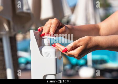 Person using hand sanitizer gel in common areas. Hand pressing on a bottle of antibacterial lotion. Close-up. Stock Photo