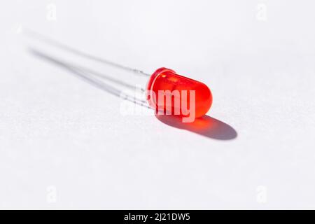 A studio portrait of a single red color LED or colored Light Emitting Diode lying on a white background, ready to be used in some kind of electronics Stock Photo