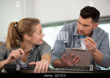 female apprentice electrician working on appliance under supervision Stock Photo
