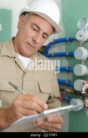 senior plumber writing on clipboard Stock Photo