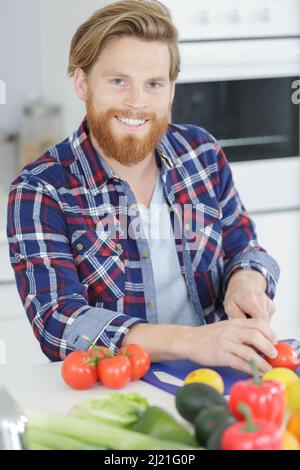 man cutting a tomato on cutting board Stock Photo