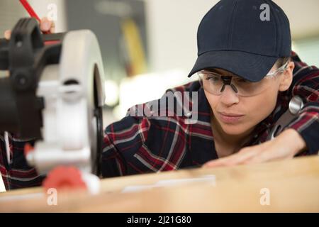 young woman using modern electric saw in the workshop Stock Photo