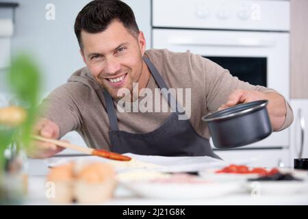 pizza chef put sauce on base in a commercial kitchen Stock Photo