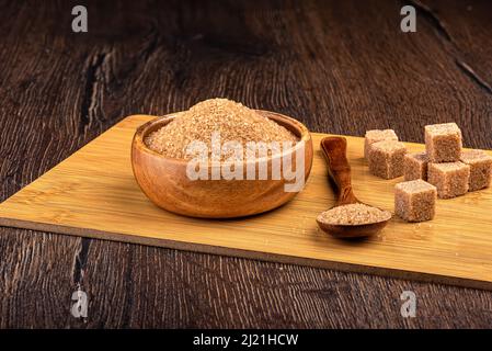 Brown cane sugar and refined sugar cubes. Sugar on a wooden spoon and in a wooden bowl. Stock Photo