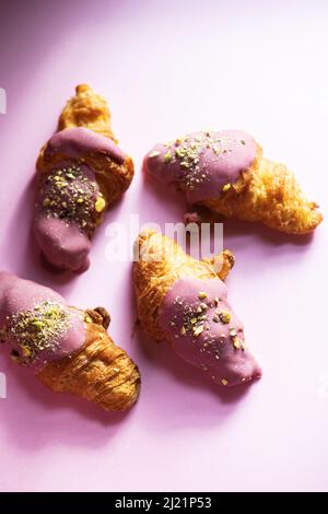 Mini-croissants with ruby chocolate and pistachios on a pink background. Top view. Stock Photo
