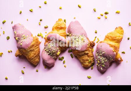 Mini-croissants with ruby chocolate and pistachios on a pink background. Top view. Stock Photo