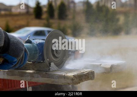 Master cuts the marble stones using an angle grinder Stock Photo