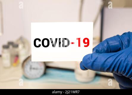 A Middle age asian woman wearing a medical face mask, holding Covid-19 card. Encourage health care from Covid 19 Corona virus, on white background. Stock Photo