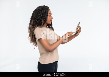 Content smiling woman typing text message or using internet on smartphone isolated over white background Stock Photo