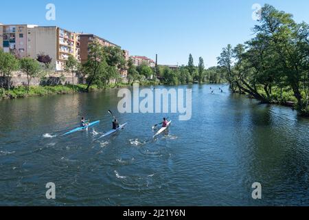 Plasencia, Spain - April 17, 2021: Several young man practices canoeing riding in his canoe navigating the Jerte river Stock Photo
