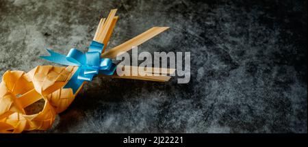 closeup of a traditional Spanish braided palm leaf, typically blessed on Palm Sunday, on a black mottled surface, in a panoramic format to use as web Stock Photo