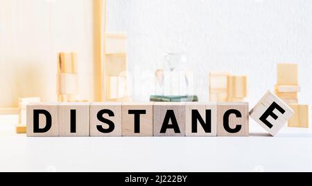 DISTANCE word written in cube on wooden floor on white background, letter blocks arranges into DISTANCE words, for adding text or other images or desi Stock Photo