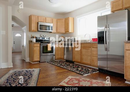 Fitted kitchen in a modern home, ovens and integrated appliances, fridge and rugs on a wood floor, Stock Photo