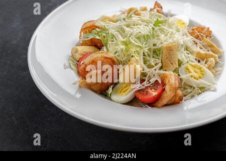 Caesar salad with shrimps, on a dark background. Stock Photo