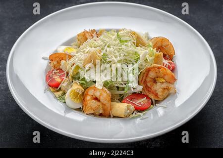 Caesar salad with shrimps, on a dark background. Stock Photo