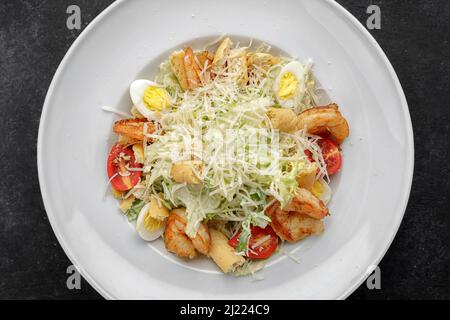 Caesar salad with shrimps, on a dark background. Stock Photo