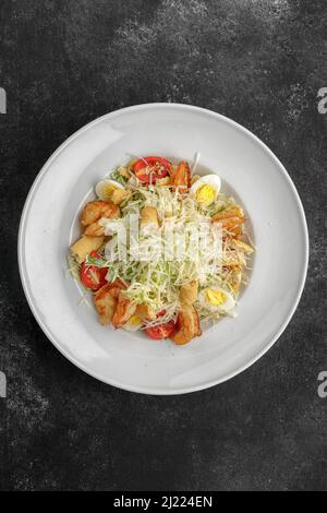 Caesar salad with shrimps, on a dark background. Stock Photo