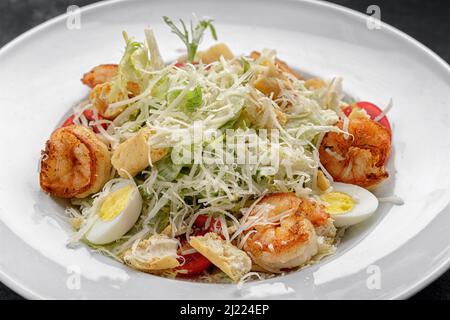Caesar salad with shrimps, on a dark background. Stock Photo