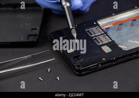 Process of mobile phone repair. Hands of a service worker repairing modern mobile phone. Stock Photo