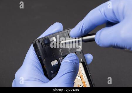 Process of mobile phone repair. Hands of a service worker repairing modern mobile phone. Stock Photo