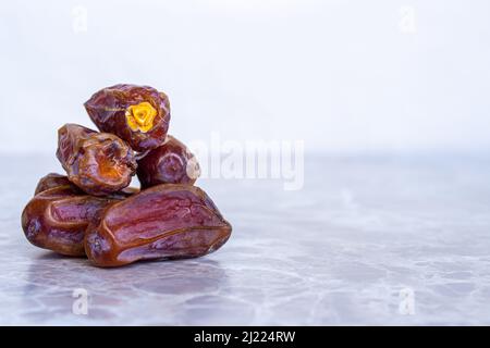 Dried date fruits on marble table. Closeup photo of ripe dates with space for text. Traditional iftar food for muslims. Stock Photo
