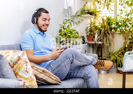 Happy man using tablet and headphones in a living room, at home. Stock Photo