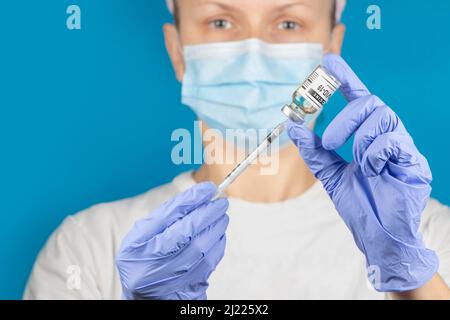 Doctor, nurse or scientist hand in blue nitrile gloves holding flu, measles, coronavirus vaccine shot for diseases outbreak vaccination, medicine and Stock Photo