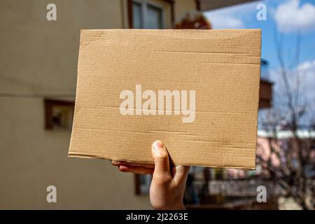 Woman holding blank placard. Demonstration or protest concept. Space for text on empty cardboard box. Stock Photo
