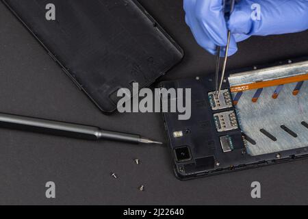 Process of mobile phone repair. Hands of a service worker repairing modern mobile phone. Stock Photo