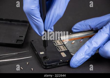 Process of mobile phone repair. Hands of a service worker repairing modern mobile phone. Stock Photo