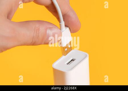 Usb cable in hand with usb connector on yellow background. Stock Photo