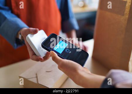 Close-up of waiter taking contactless smartphone payment from costumer in take away restaurant. Stock Photo