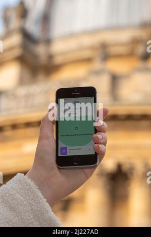 Using the NHS Covid app on an iPhone outside the Radcliffe Camera, Oxford, UK Stock Photo