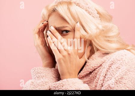 Shocked young lady feeling frightened, covering face in fear, standing over pink studio background Stock Photo