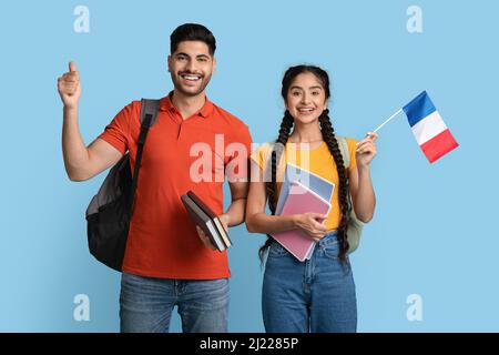 Study In France. Arab Man And Woman Holding Workbooks And French Flag Stock Photo