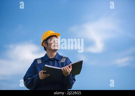 An Engineer is holding a document and looking away. Stock Photo