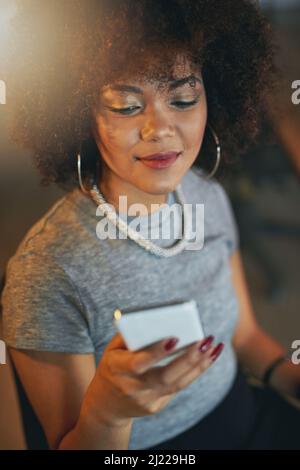Just finished my shift, on my way home. Shot of a young woman using a phone during a late shift at the office. Stock Photo