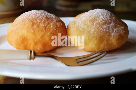 Pair of tasty fresh fried Georgian doughnuts sprinkled with powdered sugar Stock Photo