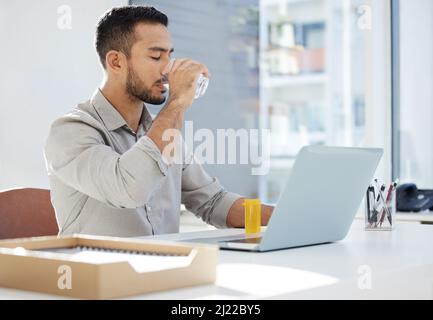 The energy levels are high. Shot of a young man using his laptop and having coffee at work in a modern office. Stock Photo